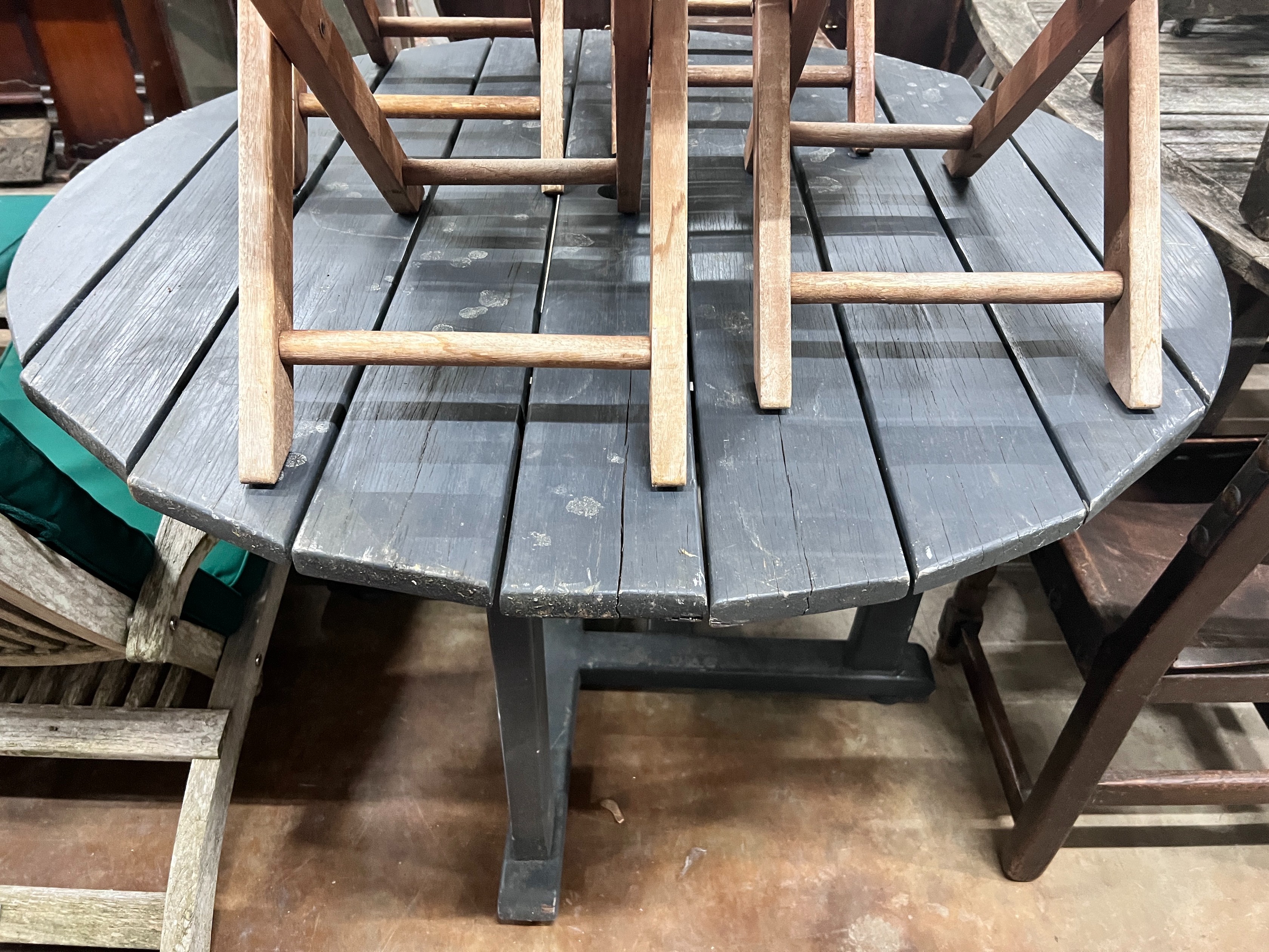 A grey stained teak circular garden table and four faded teak folding chairs, table diameter 120cm *Please note the sale commences at 9am.